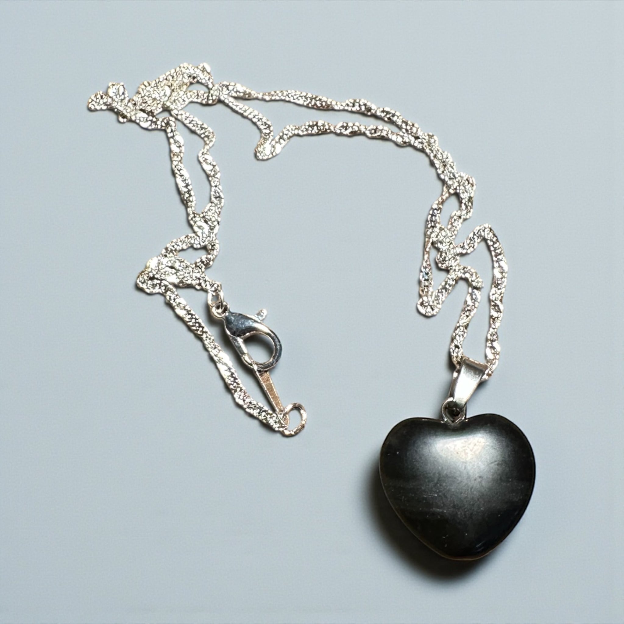 My Two Daughters Jewelry - Heart-shaped black banded agate pendant on a silver chain against a light gray background