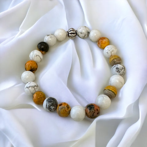 My Two Daughters Jewelry - A bracelet made with multicolored round beads in shades of white, orange, and gray, displayed on a white fabric surface.