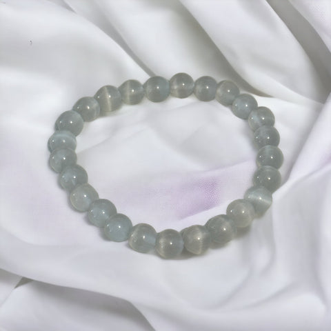 My Two Daughters Jewelry - A bracelet made of round Cat's Eye Quartz stones, displayed on a white silky surface.
