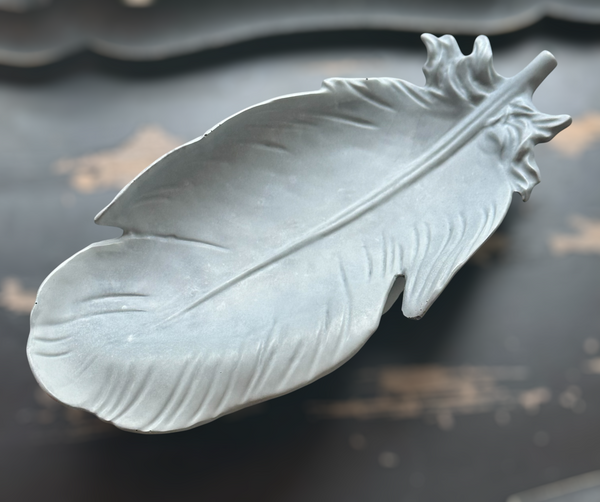 My Two Daughters Jewelry - Decorative feather on a textured surface