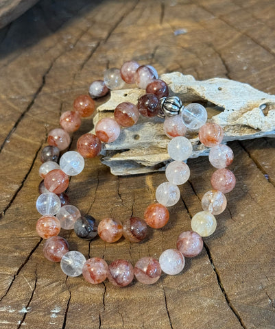 My Two Daughters Jewelry - A bracelet made of fire quartz stones, displayed on a wooden surface with a piece of wood in the background.
