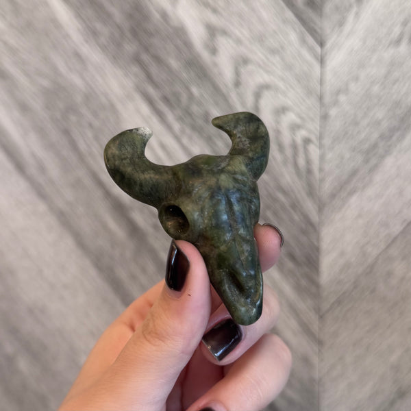 Kelowna Crystal Cave - Hand holding a small green stone sculpture against a gray background