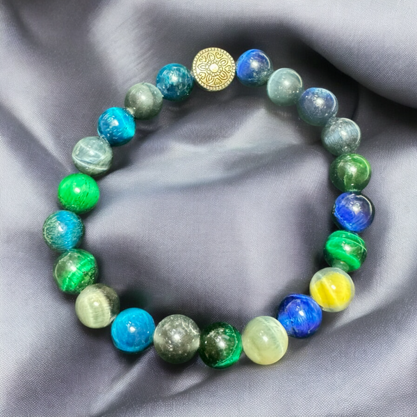 My Two Daughters Jewelry - A beaded bracelet with green and blue colors, featuring a golden spherical charm, displayed on a silky gray background.