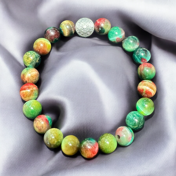 My Two Daughters Jewelry - A beaded bracelet with green and red colors, featuring a golden spherical charm, displayed on a silky gray background.