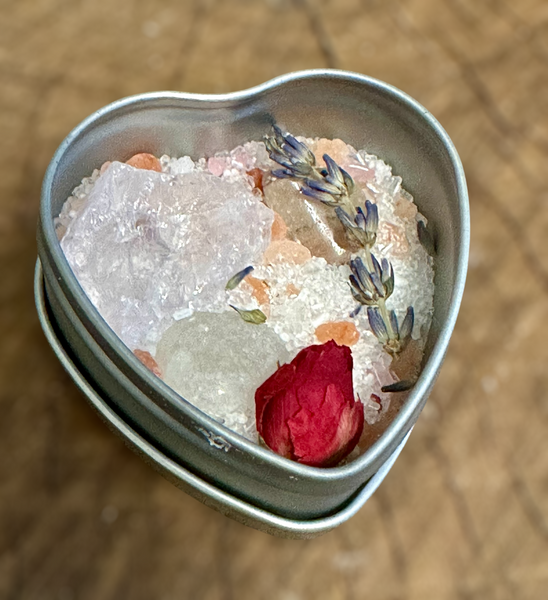 Kelowna Crystal Cave - Heart-shaped container with bath salts, flowers, and a rose petal on a wooden surface