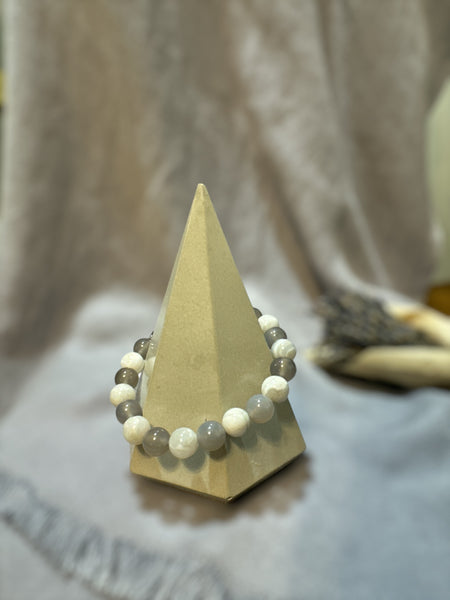 My Two Daughters Jewelry - A bracelet with gray and white agate beads displayed on a triangular stand.