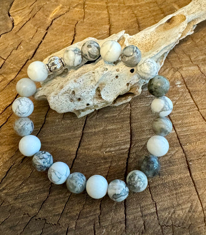 My Two Daughters Jewelry - A bracelet made of howlite and map jasper stones, displayed on a wooden surface with a piece of driftwood in the background.