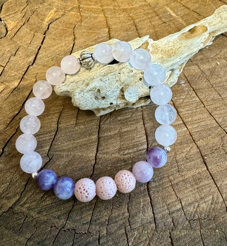 My Two Daughters Jewelry - A bracelet with round beads in shades of pink and purple, featuring a mix of smooth and textured stones, displayed on a wooden surface.