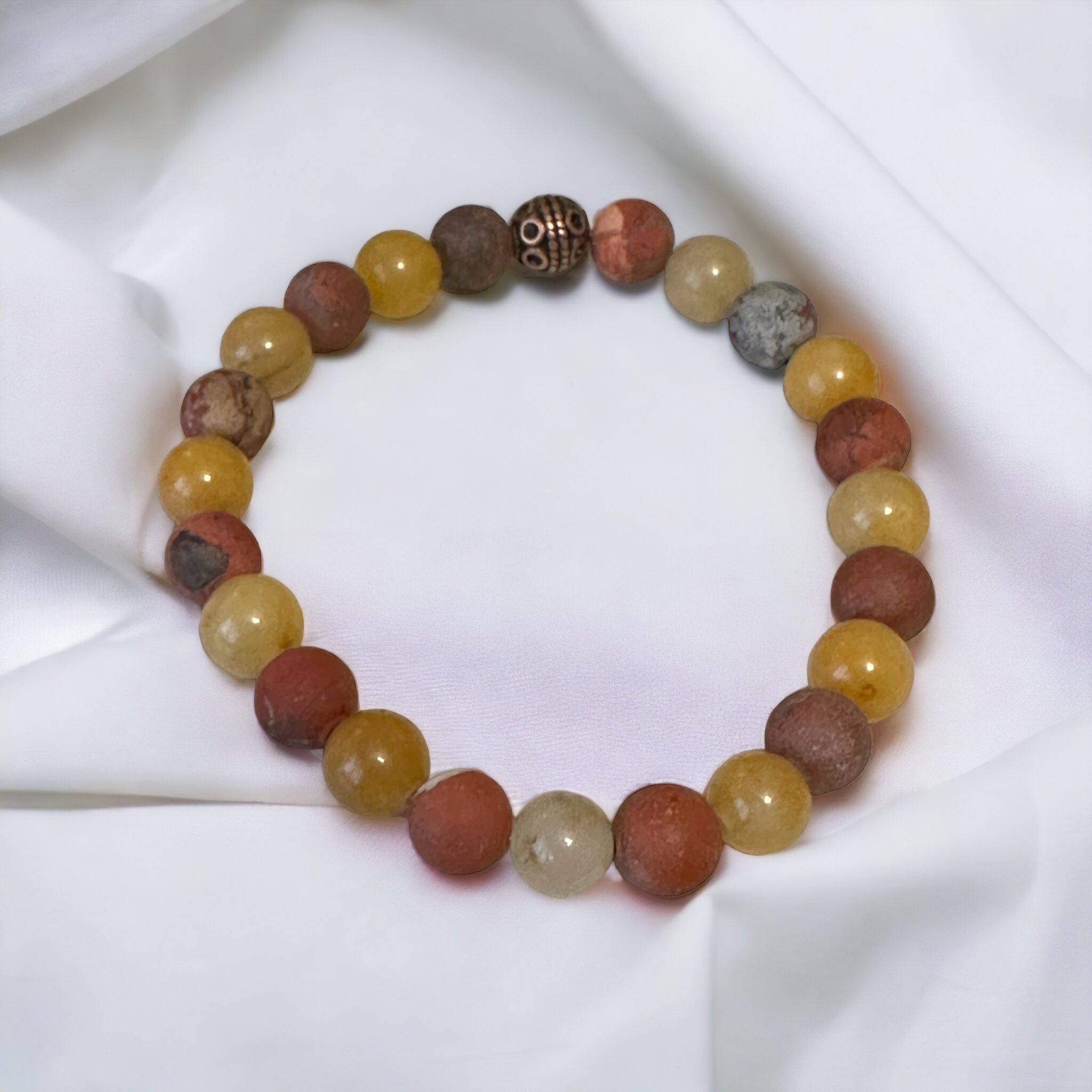 My Two Daughters Jewelry - A bracelet with round matte red jasper and yellow aventurine beads, displayed on a white fabric surface.