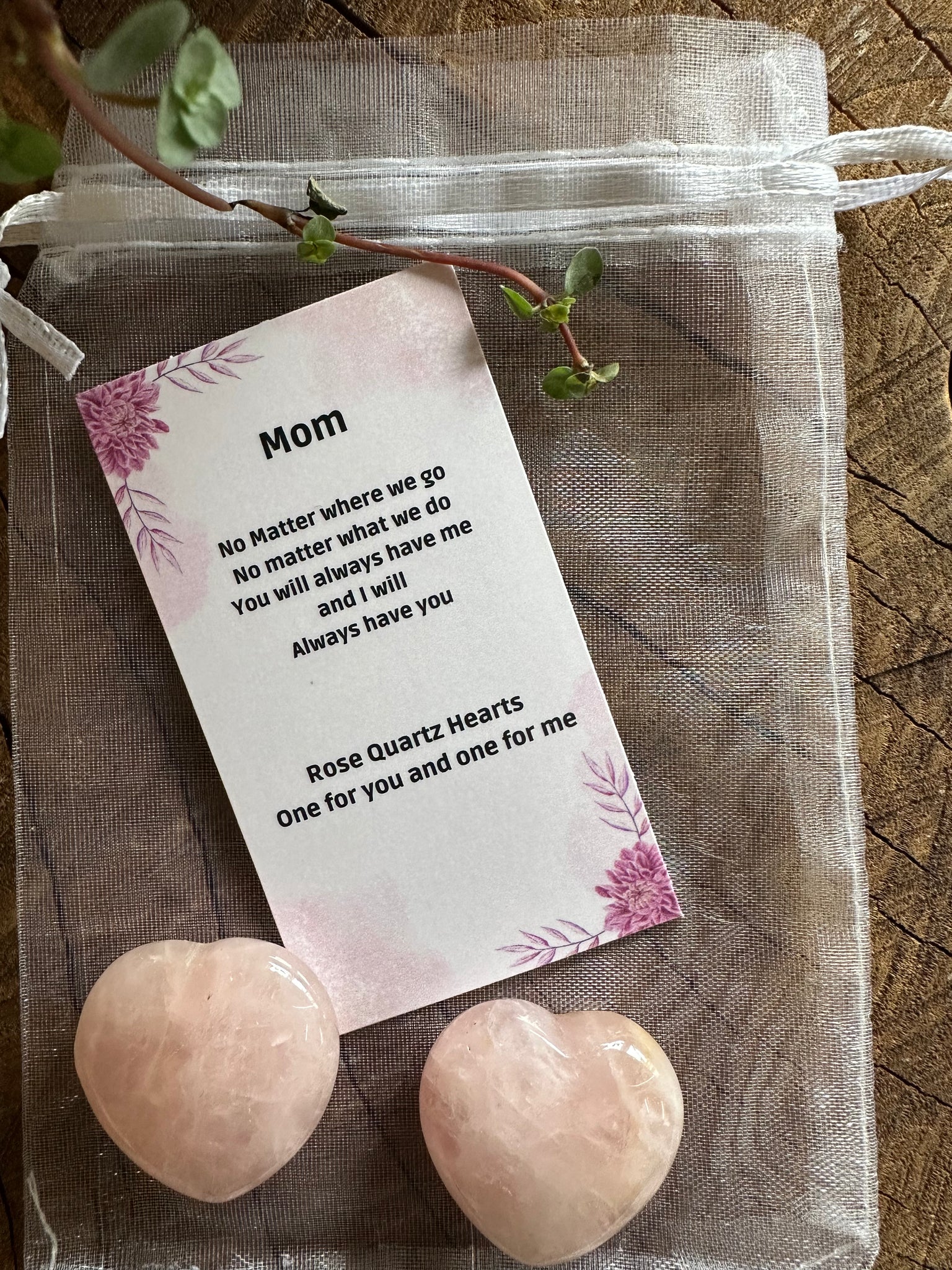 Kelowna Crystal Cave - Two rose quartz hearts placed on top of a textured fabric, with an attached note card that reads 'Mom' and includes a quote about love.