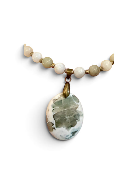 My Two Daughters Jewelry - A beaded necklace featuring a large, irregular-shaped green and white marbled stone pendant, suspended from a strand of cream, beige, and light green beads with small gold spacer rings, set against a plain white background.