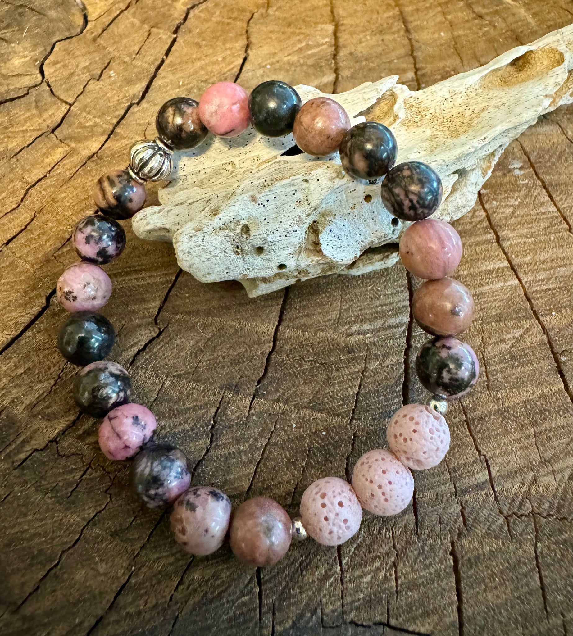 My Two Daughters Jewelry - A bracelet made with round beads of varying shades of pink, brown, and black, displayed on a wooden surface.