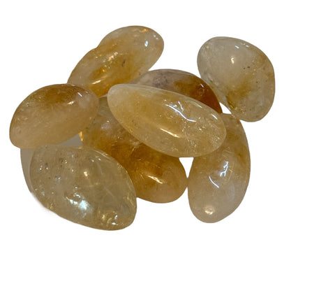 Kelowna Crystal Cave - A collection of polished citrine stones of varying sizes with a golden yellow hue, arranged in a pile.