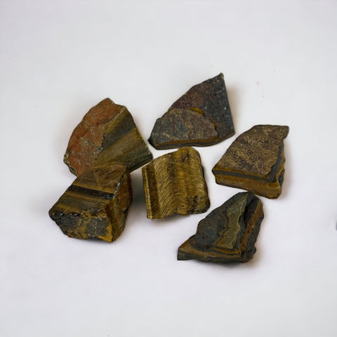 Kelowna Crystal Cave - A collection of raw tigers eye stones with a smooth, shiny surface on a white background.