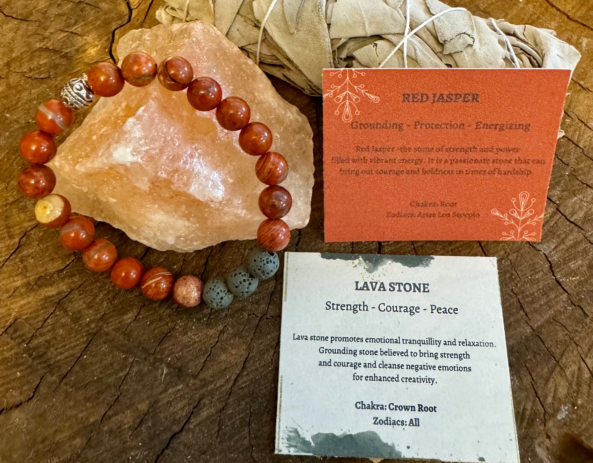 My Two Daughters Jewelry - A Red Jasper bracelet displayed alongside a piece of Lava stone and cards describing the properties of each. The Lava stone is used for promoting emotional tranquility and relaxation, while the Red Jasper is known for its strength, courage, and power.