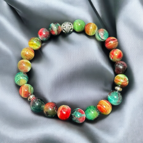 My Two Daughters Jewelry - A beaded bracelet with green and red colors, featuring a golden spherical charm, displayed on a silky gray background.