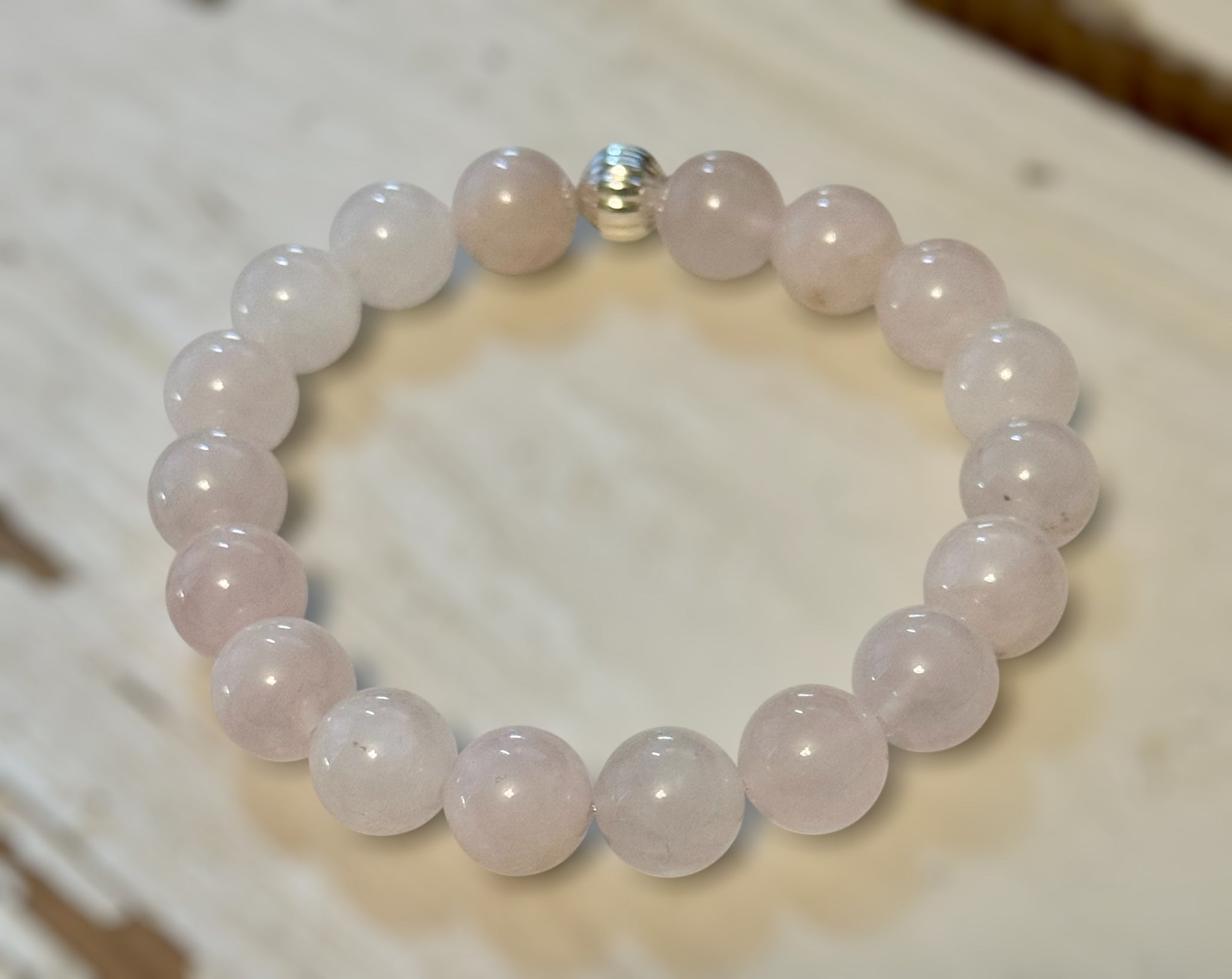 My Two Daughters Jewelry - Rose quartz beaded bracelet on a wooden surface