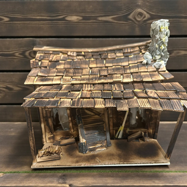 LB - Model of a rustic wooden cabin with a thatched roof on a wooden surface