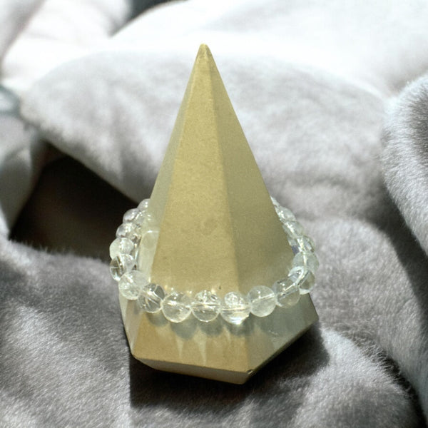 My Two Daughters Jewelry - A clear quartz bracelet displayed on a triangular stand