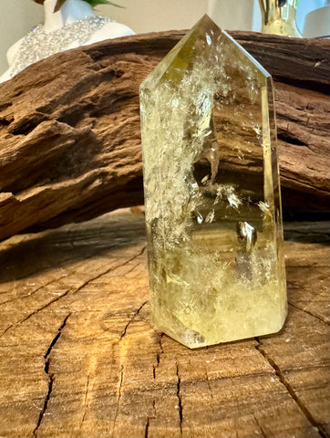 Kelowna Crystal Cave - A Smoky Citrine crystal tower placed on a wooden surface with a piece of driftwood in the background.
