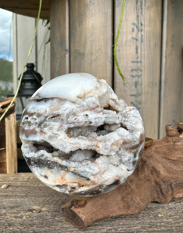 Kelowna Crystal Cave - A Sphalerlite crystal sphere with a layered white, brown, and gray design, placed on a wooden surface.
