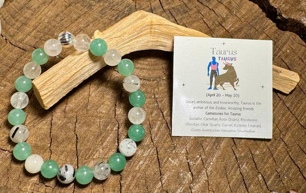 My Two Daughters Jewelry - Green and white beaded bracelet on a wooden surface with a Taurus card.