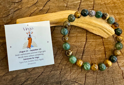 My Two Daughters Jewelry - A colorful beaded bracelet displayed on a wooden surface, with a card indicating it is a Virgo-themed bracelet for August 23 to September 22. The bracelet and card are presented alongside a description of the product's properties.