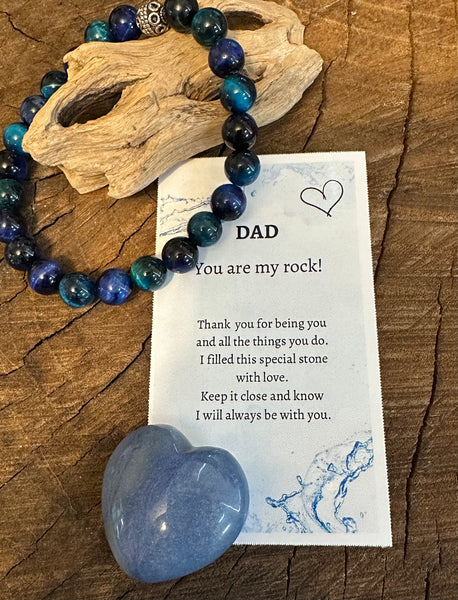 Fancy Beads - A bracelet with blue tigers eye stones placed on a wooden surface, accompanied by a Father's Day card with a heart symbol and a pocket heart stone.