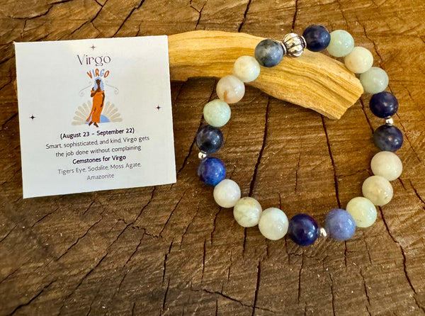 My Two Daughters Jewelry - A colorful beaded bracelet displayed on a wooden surface, with a card indicating it is a Virgo-themed bracelet for August 23 to September 22. The bracelet and card are presented alongside a description of the product's properties.