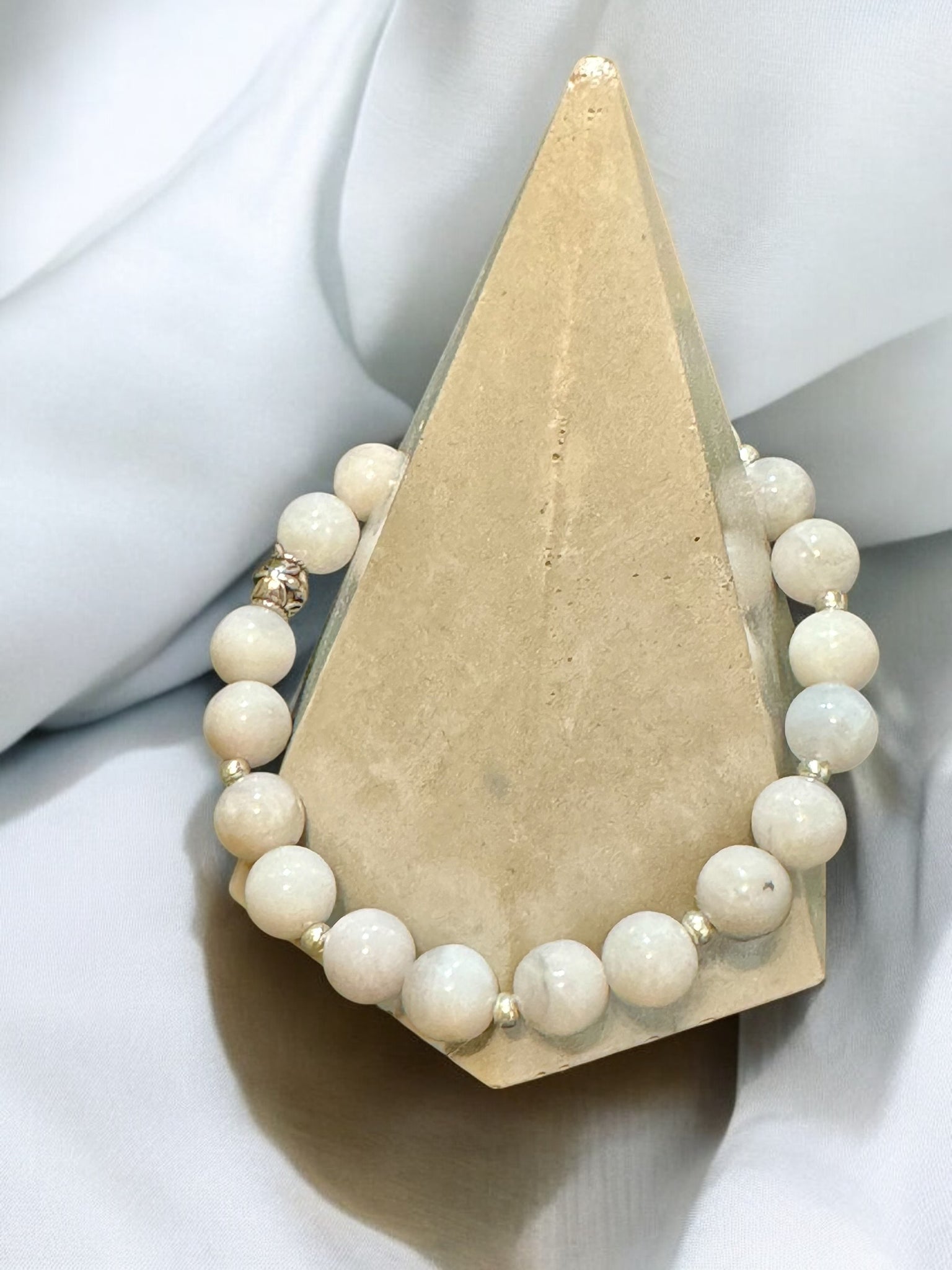 My Two Daughters Jewelry - A white crazy lace agate bracelet with silver spacer beads displayed on a beige stand.