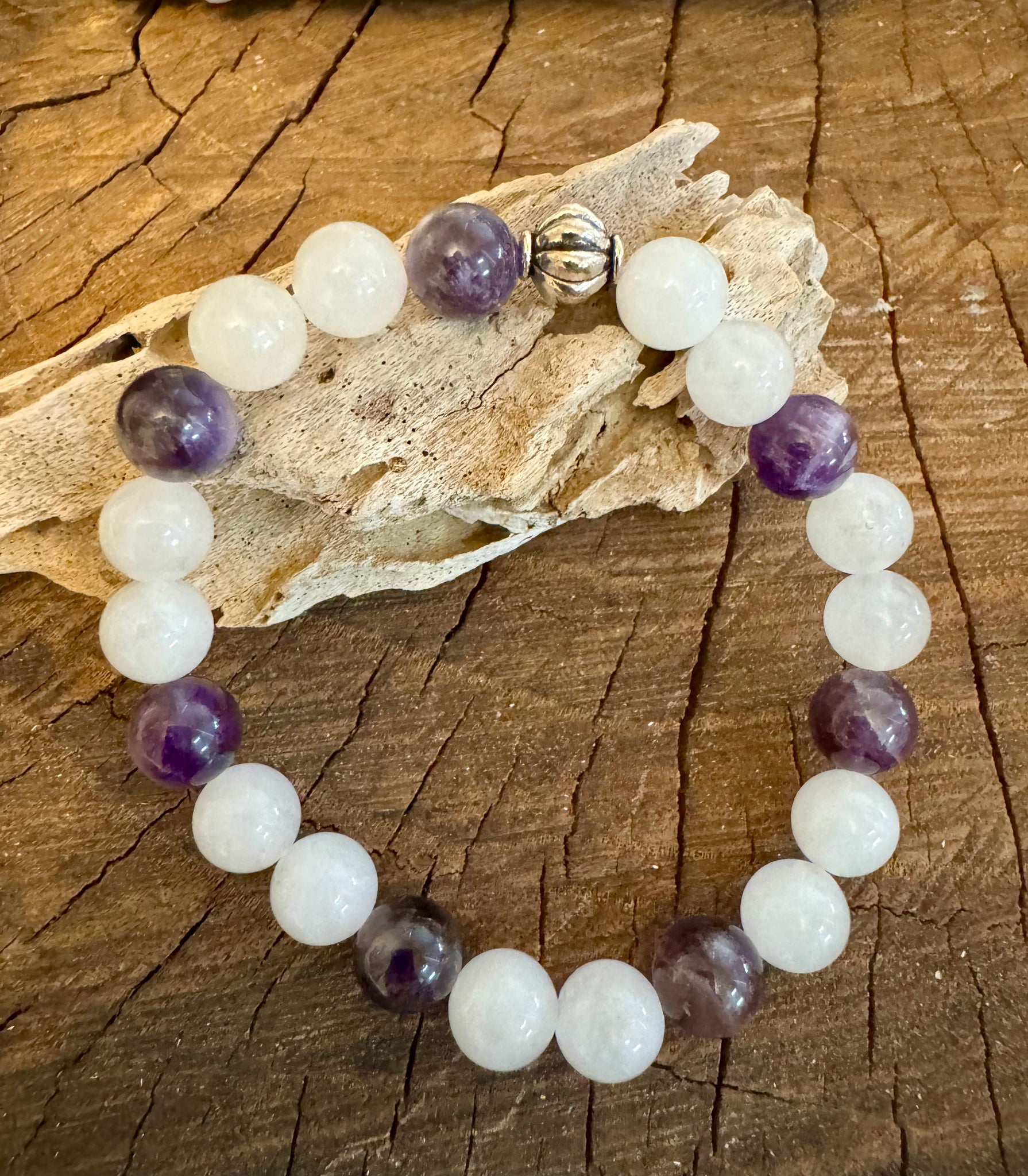 My Two Daughters Jewelry - A bracelet with spherical white jade and amethyst beads displayed on a wooden surface.