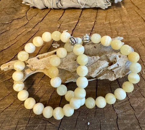My Two Daughters Jewelry - A yellow calcite bracelet laid out on a wooden surface, with the bracelet displaying smooth, round beads and a silver clasp.