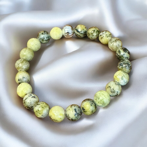 My Two Daughters Jewelry - A bracelet made of yellow turquoise beads displayed on a silky surface.