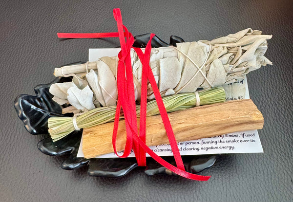 TRUE ART KELOWNA - Smudging tools including sage, sweetgrass, and red ribbon on a black dish with instructions.