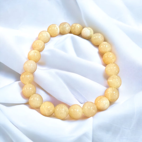 My Two Daughters Jewelry - A bracelet made of round yellow topaz stones, displayed on a white fabric surface.
