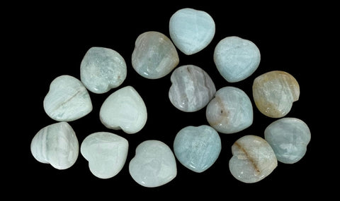 Kelowna Crystal Cave - A collection of heart-shaped Amazonite stones arranged on a dark surface.