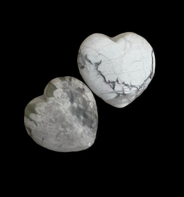 Kelowna Crystal Cave - Two polished howlite hearts on a black background, one displayed in front and the other in side view, showcasing the web-like pattern typical of the mineral howlite.