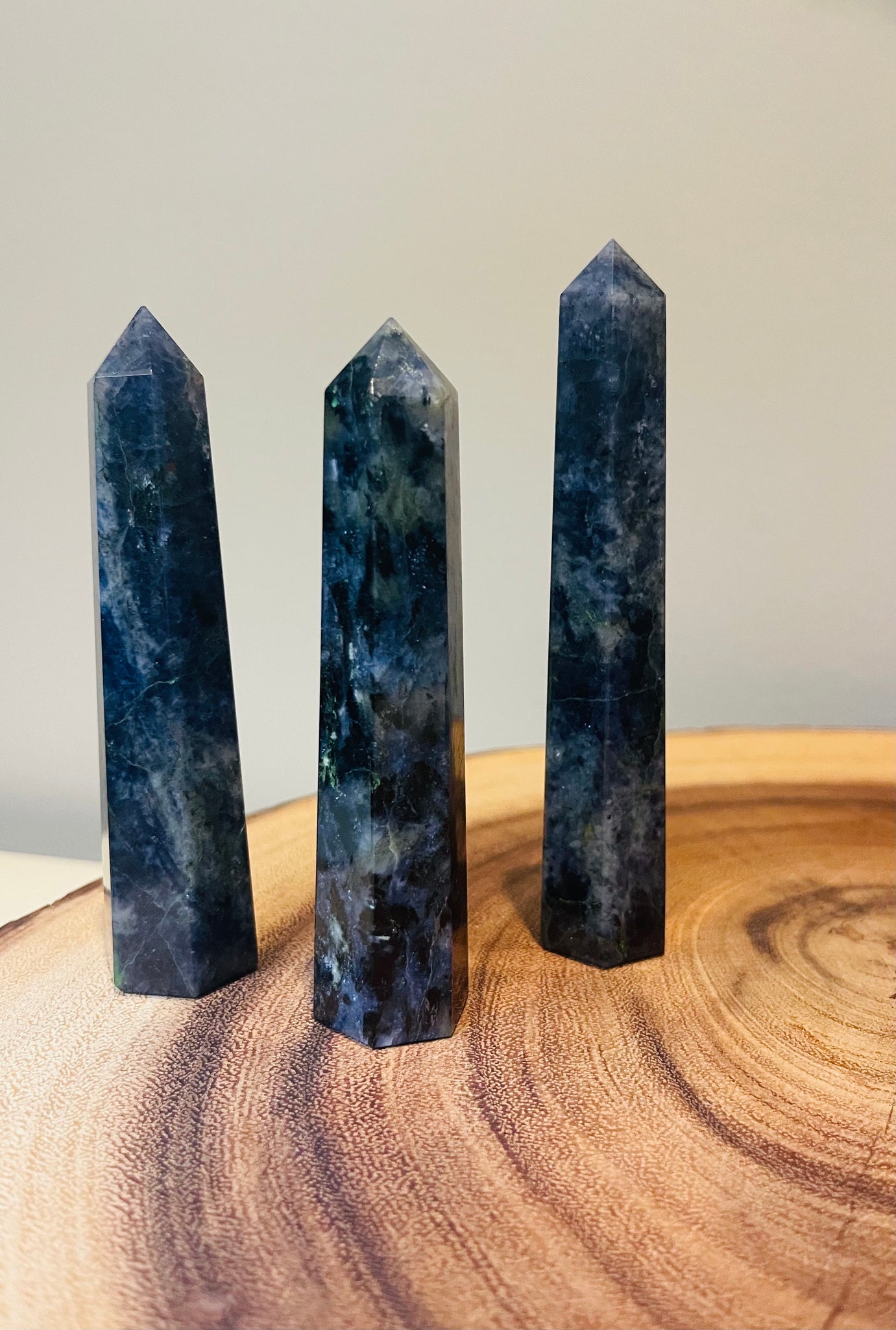 Kelowna Crystal Cave - Three polished Lolite crystal points standing upright on a wooden surface.