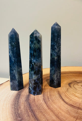 Kelowna Crystal Cave - Three polished Lolite crystal points standing upright on a wooden surface.