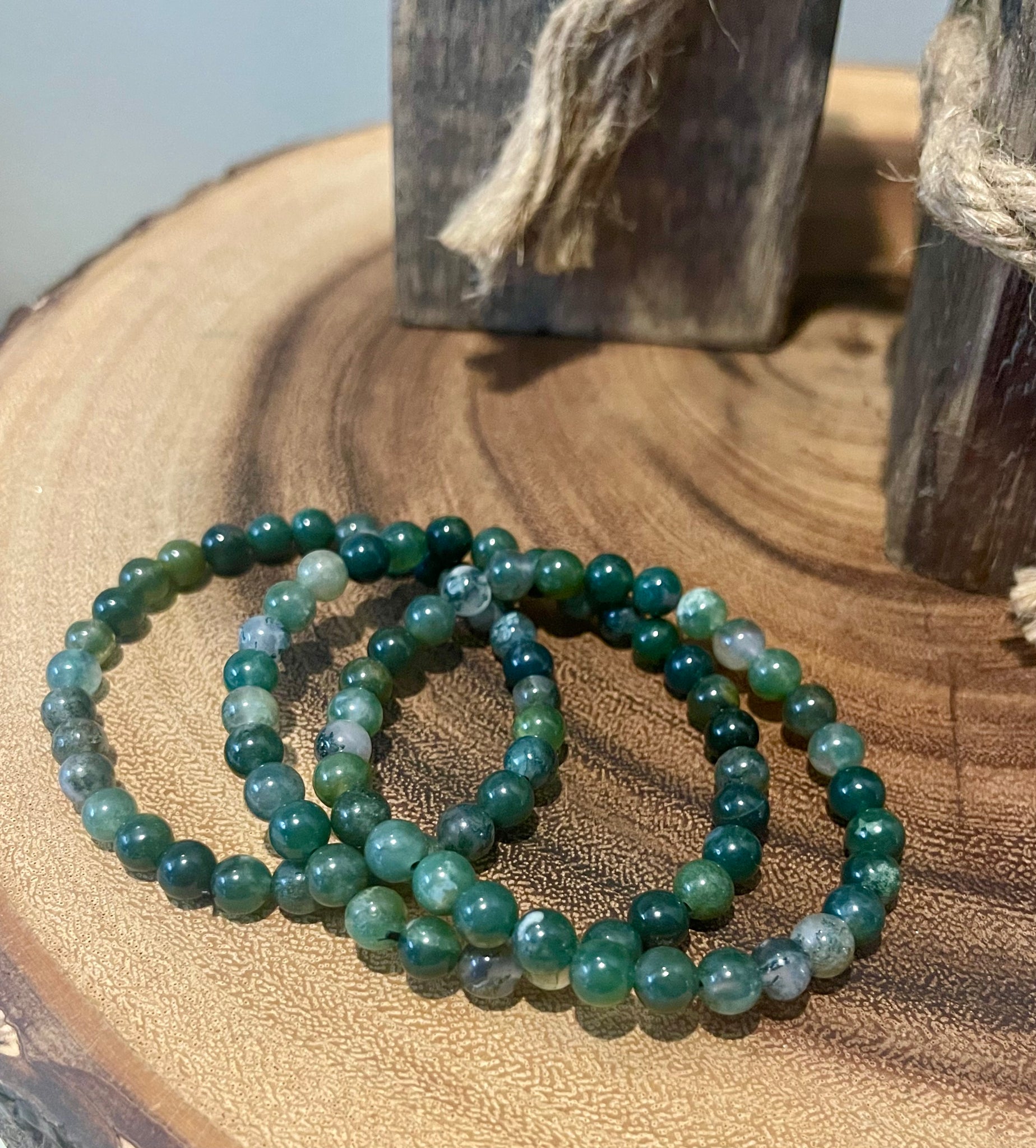 My Two Daughters Jewelry - A green moss agate bracelet displayed on a wooden surface.