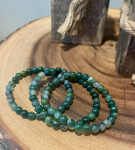 My Two Daughters Jewelry - A green moss agate bracelet displayed on a wooden surface.