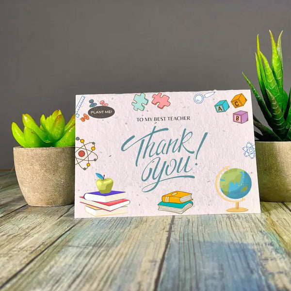 Plantable Greetings - A plantable greeting card with the word 'mother' printed on it, placed on a wooden surface with two potted plants in the background.