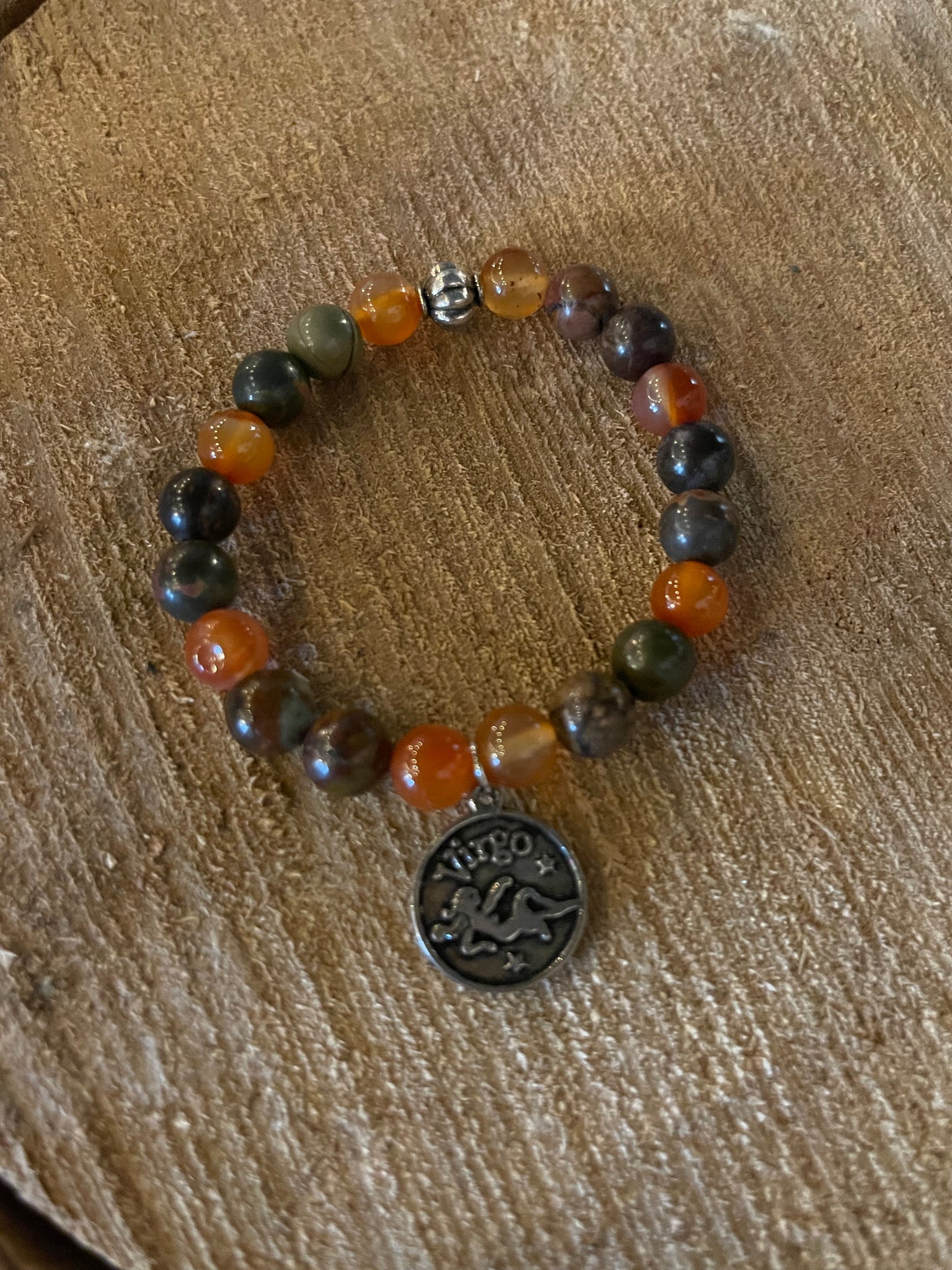 My Two Daughters Jewelry - A multicolored beaded bracelet with a silver-colored Virgo zodiac charm, displayed on a wooden surface.